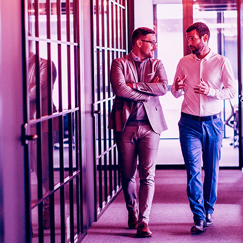 Two men walking in a work office square