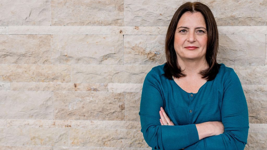 Woman in blue shirt against a wall